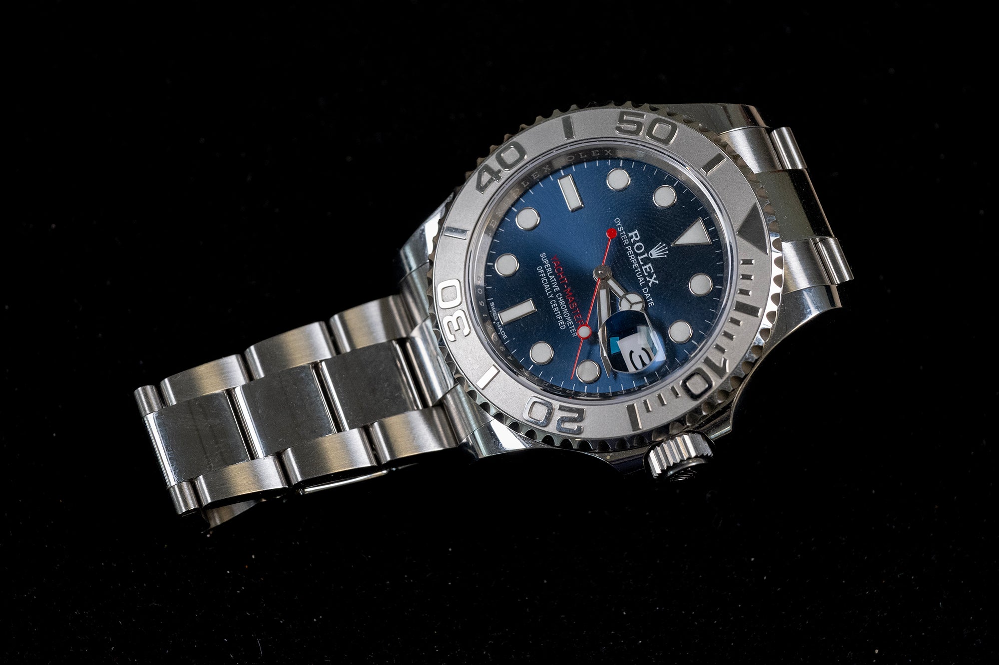An Rolex Submariner Date watch with a stainless steel Oyster bracelet, featuring a blue dial, blue bezel insert, and a silver-tone bezel with black numerals, photographed on a solid black background.