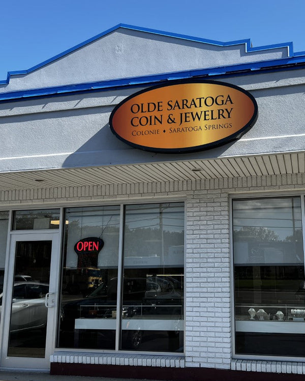 a white retail building with olde saratoga coin and jewelry sign. 